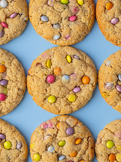 Flat lay baked gingerbread rainbow cookies on light blue background